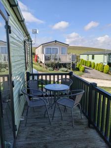 a patio with chairs and a table on a deck at Caravan - Sleeps 6 - Sea Views - Dog Friendly in Flamborough
