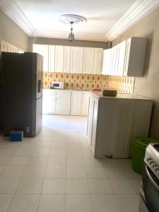 a kitchen with white cabinets and a black refrigerator at Hôtel Ami Bamba in Mbour
