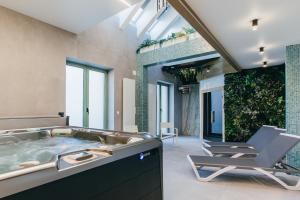 une salle de bains avec une baignoire jacuzzi et une chaise dans l'établissement NOZON Apartments & Wellness, à Odorheiu Secuiesc