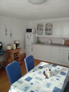 ザスニッツにあるFerienwohnung Straßburgのキッチン(テーブル、青い椅子、白い冷蔵庫付)