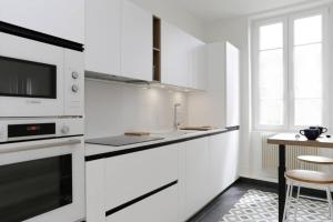 een keuken met witte kasten en een aanrechtblad bij La Chouette in Dijon