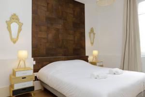 een slaapkamer met een wit bed met 2 nachtkastjes en 2 lampen bij La Chouette in Dijon