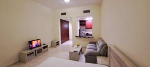 a living room with a couch and a tv at Studio flat DG079, Close to The Gardens Metro 3 min walkable in Dubai