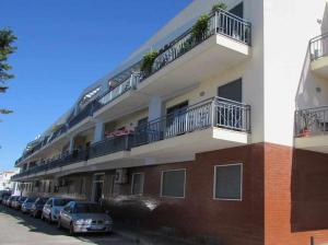 a building with cars parked in a parking lot at Mar e Sol by - T3 , wi-fi e estacionamento in Quarteira
