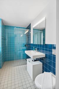 a blue tiled bathroom with a sink and a toilet at Zurich Flat: Central & Lake Convenience in Zürich