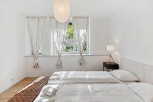 a white bedroom with two beds and a window at Zurich Flat: Central & Lake Convenience in Zürich