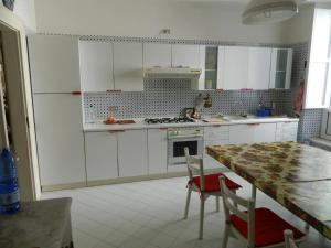 eine Küche mit weißen Schränken und einem Tisch mit Stühlen in der Unterkunft Casa Vela in Ariano Irpino