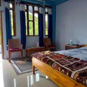 a bedroom with a bed with blue walls and windows at VIbe n Joy Homestay in Cherrapunji