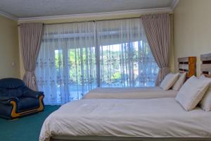 um quarto com 2 camas e uma grande janela em Unique Bed and Breakfast em Harare