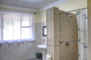 uma casa de banho com um chuveiro e um lavatório. em Unique Bed and Breakfast em Harare