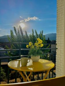una mesa amarilla con una taza y flores en el balcón en SolGredos I, en Arenas de San Pedro