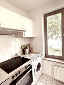 Gemütliche Wohnung mit Balkon in Schönefeld في شونيفيلد: مطبخ مع غسالة ملابس ونافذة