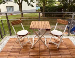 2 Stühle und ein Holztisch auf einer Terrasse in der Unterkunft Gemütliche Wohnung mit Balkon in Schönefeld in Schönefeld