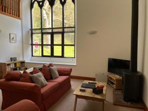 a living room with a red couch and a tv at Lairds and Keepers Apartments in Dunkeld