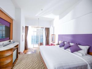 a hotel room with a large bed and a flat screen tv at Novotel Nha Trang in Nha Trang