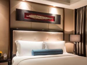 um quarto com uma grande cama branca e uma almofada azul em Pullman Shanghai Jingan em Xangai