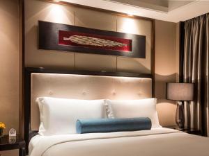 a bedroom with a large white bed with a blue pillow at Pullman Shanghai Jingan in Shanghai