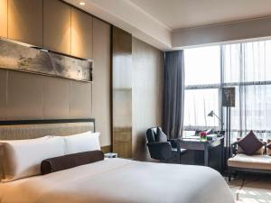 a hotel room with a bed and a desk at Pullman Shanghai Jingan in Shanghai