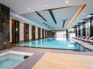 a swimming pool in a building with chairs at Pullman Shanghai Jingan in Shanghai