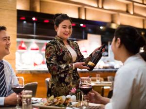 a woman holding a bottle of wine in a restaurant at Pullman Shanghai Jingan in Shanghai