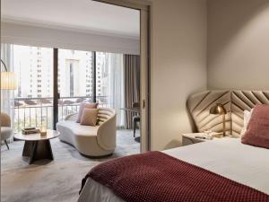 een hotelkamer met een bed, een stoel en een raam bij The Playford Adelaide - MGallery in Adelaide