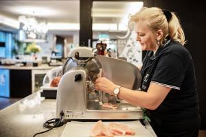 una mujer usando una máquina de coser en un mostrador en Apart Hotel Legendär, en Steindorf am Ossiacher See