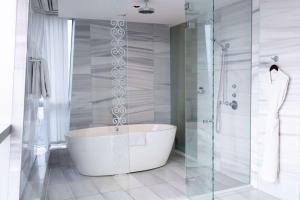 uma casa de banho com uma banheira e um chuveiro em vidro. em Hyatt Regency Dushanbe em Dushanbe