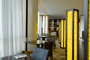 une salle à manger avec des tables, des chaises et des lumières jaunes dans l'établissement Hyatt Regency Dushanbe, à Douchanbé