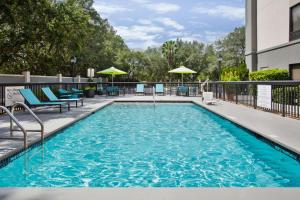 a swimming pool with chairs and umbrellas on a building at Hampton Inn & Suites Lady Lake/The Villages in The Villages