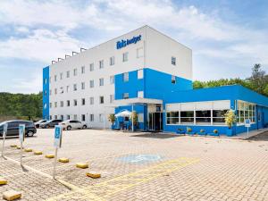 a large blue and white building with a parking lot at ibis budget Piracicaba in Piracicaba