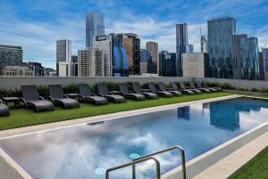a rooftop pool with chairs and a city skyline at Wyndham Hotel Melbourne in Melbourne