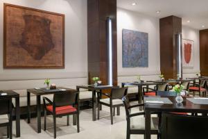 a restaurant with tables and chairs and a painting on the wall at NH Collection Palacio de Aranjuez in Aranjuez