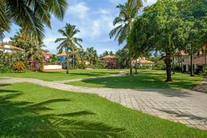a path in a park with palm trees and houses at Radisson Blu Resort, Goa in Cavelossim +258 photos