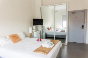 a bedroom with a white bed and a mirror at Exchange Hotel Goulburn in Goulburn