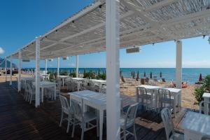 a deck with tables and chairs on the beach at Hotel Oasi Di Kufra in Sabaudia