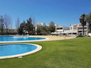 um par de piscinas num campo de relva em Eden Jasmim by FHR em Quarteira