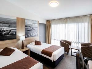 a hotel room with two beds and a desk at Mantra Bathurst in Bathurst