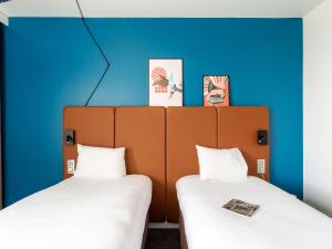 2 camas en una habitación con paredes azules en Ibis Rouen Centre Rive Gauche Mermoz, en Rouen