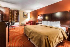 a hotel room with a large bed and a chair at Wingate by Wyndham Marietta Conference Center Ohio in Marietta