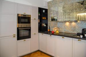 a kitchen with white cabinets and black counter tops at Maya's Flats & Resorts 34 - Chmielna 73 in Gdańsk