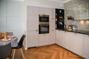a kitchen with white cabinets and a table and a table and a table at Maya's Flats & Resorts 34 - Chmielna 73 in Gdańsk