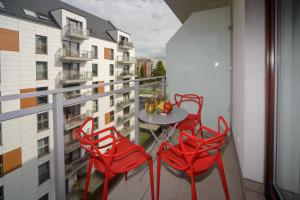 a balcony with red chairs and a table on a building at Maya's Flats & Resorts 34 - Chmielna 73 in Gdańsk