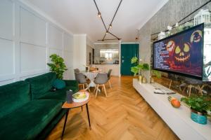 uma sala de estar com um sofá verde e uma televisão em Maya's Flats & Resorts 34 - Chmielna 73 em Gdansk