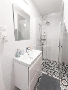 een witte badkamer met een wastafel en een douche bij Hlavna Apartment II Košice in Košice