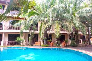 a swimming pool in front of a building with palm trees at Thai Pura Resort in North Pattaya