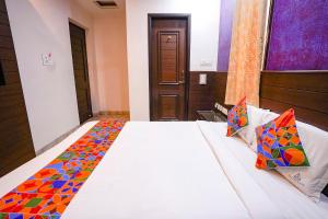 um quarto com uma cama branca e almofadas coloridas em FabExpress MM Residency em Chennai