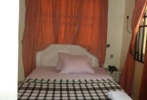 a bed with an orange curtain and two pillows on it at Room in Lodge - Vision Serviced Apartments in Asaba