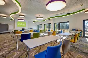 a classroom with tables and chairs and a screen at Explorer Hotel Garmisch in Farchant
