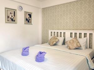 Dos camas en una habitación con toallas púrpuras. en Phureya Ville, en Ban Map Khla