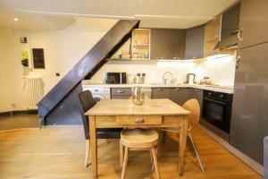 uma cozinha com uma mesa de madeira com cadeiras e uma escada em La maison verte em Annecy
